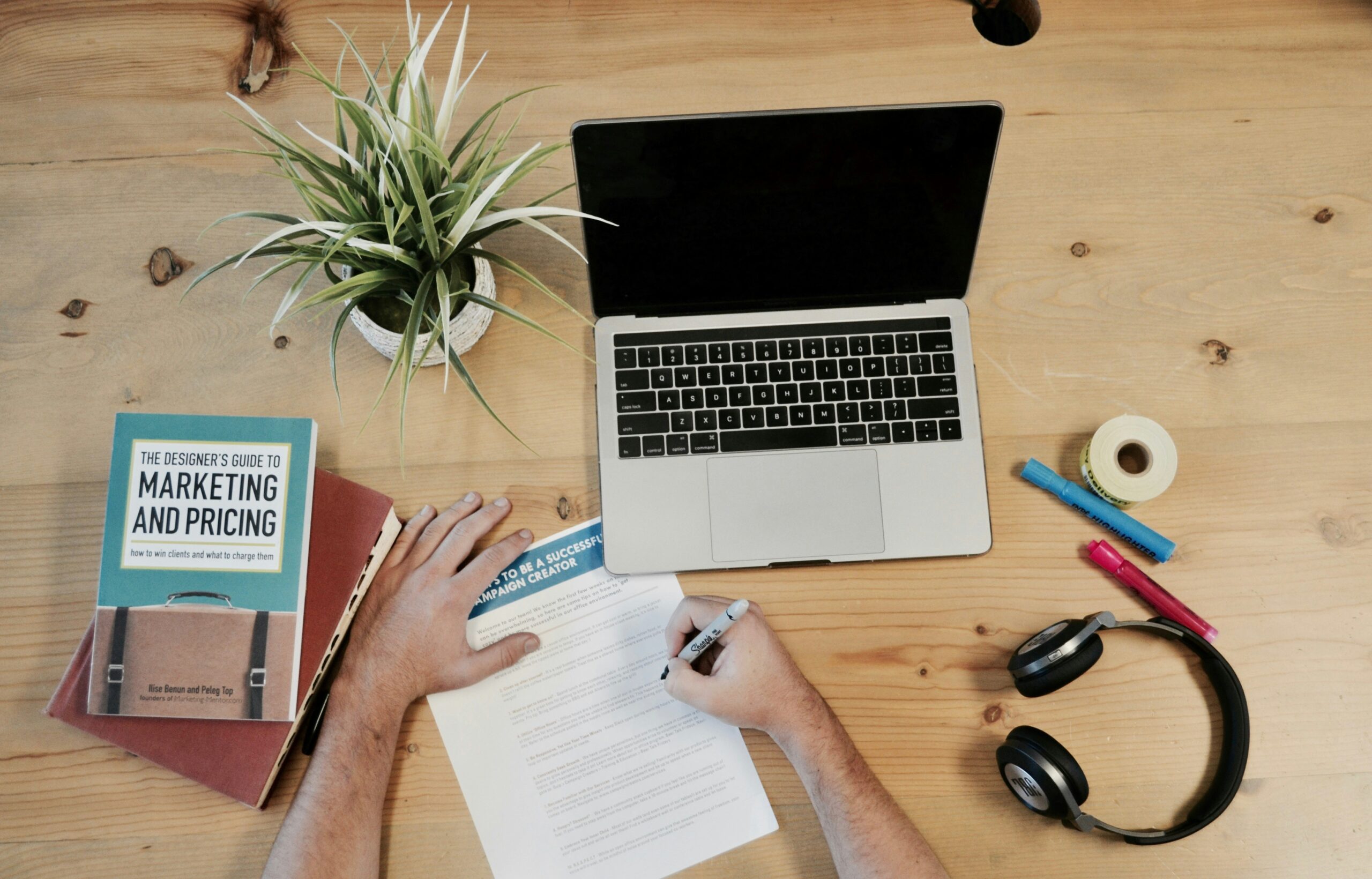 Person pictured utilizing a desk workspace with marketing books and other marketing materials.