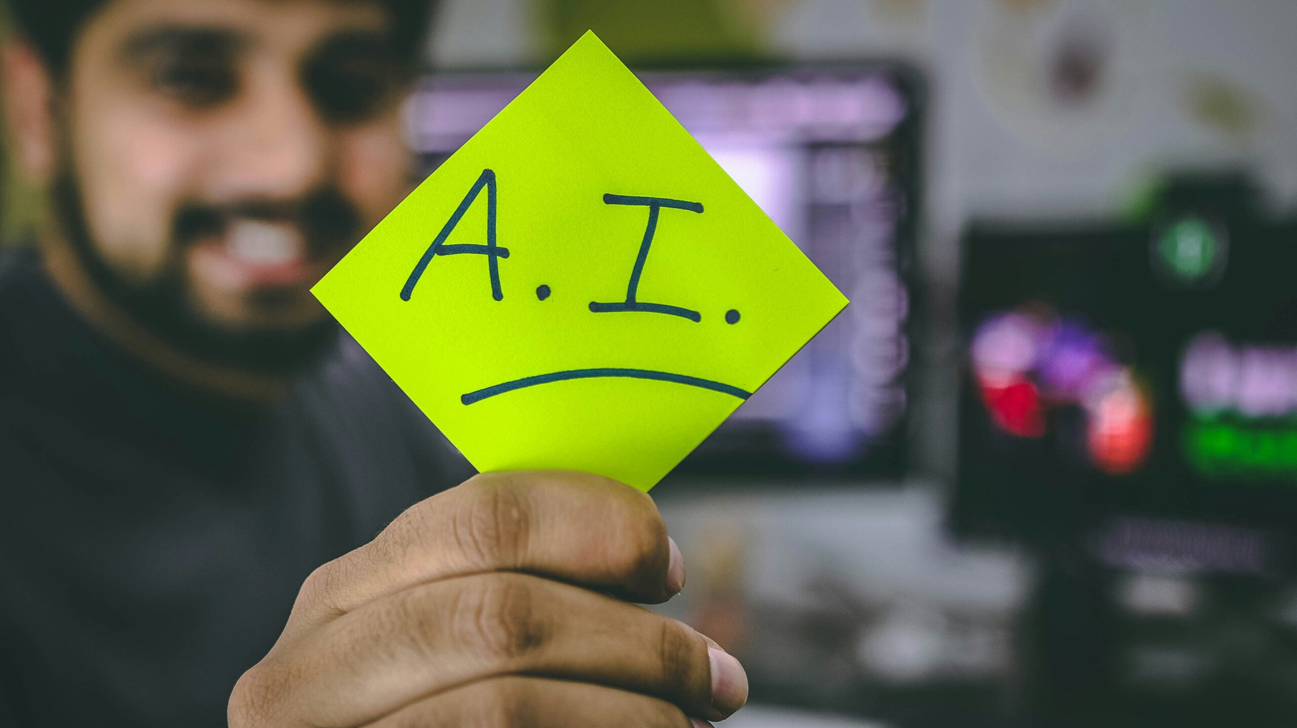 Man holding sticky note with A.I. written on it.