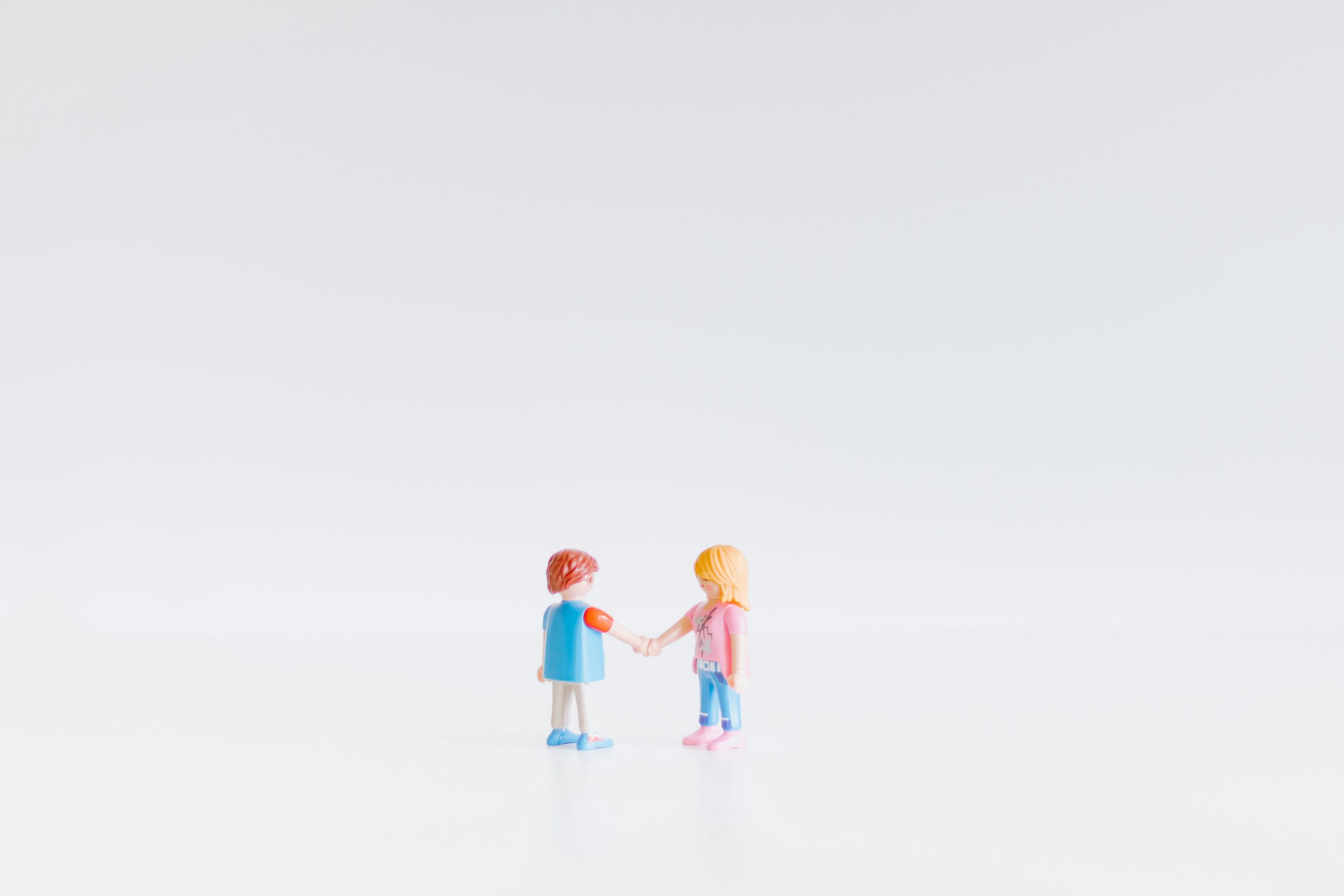 Two toy figures shaking hands in agreement.